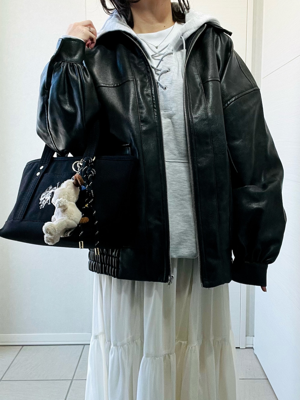 ブラック系のブルゾン、グレー系のパーカー、ホワイト系のスカートを着用したレディースの冬コーディネートの2枚目の写真