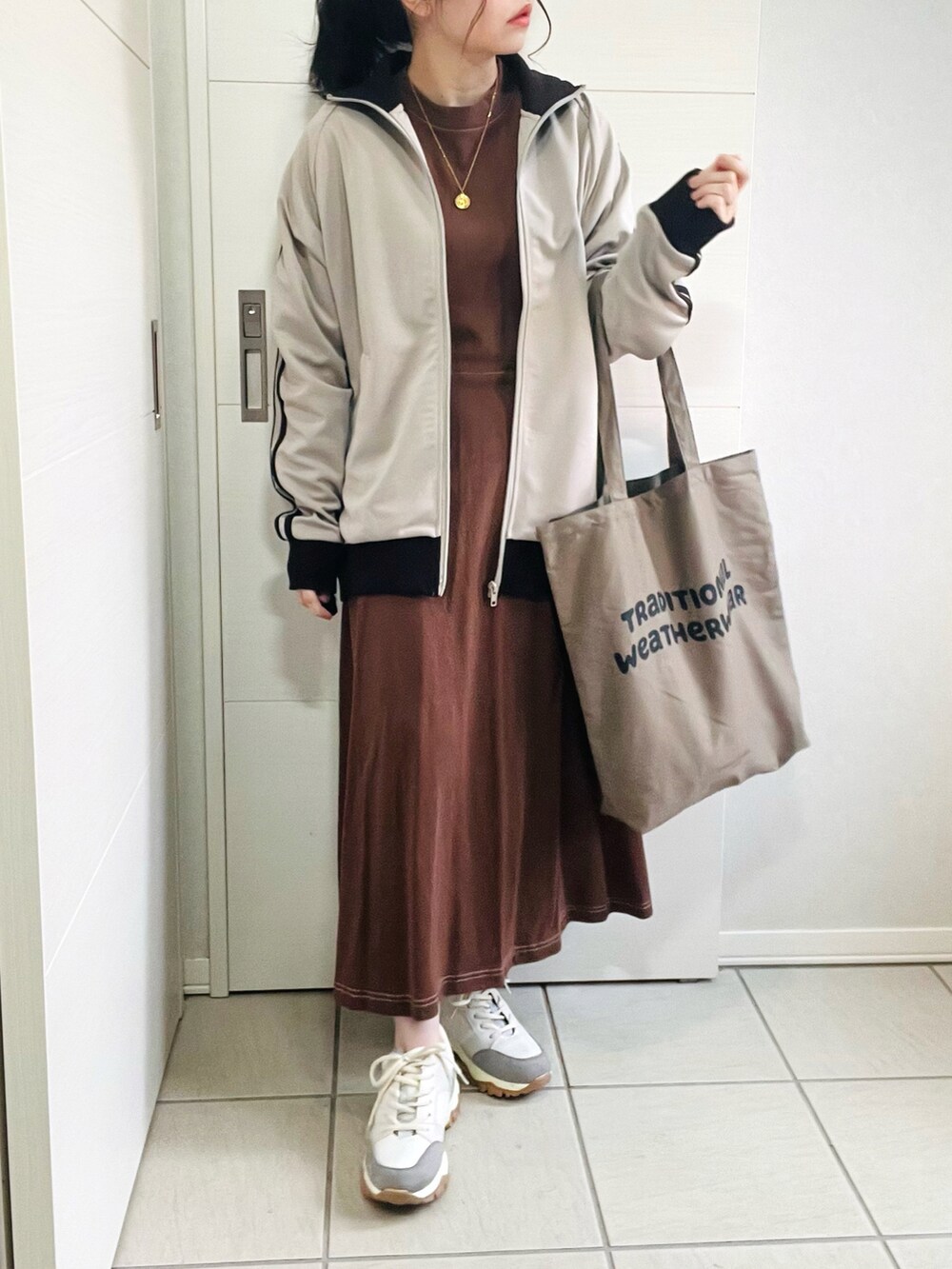 ベージュ系のジャージ、ブラウン系のワンピース、ベージュ系のスニーカーを着用したレディースの秋コーディネートの3枚目の写真
