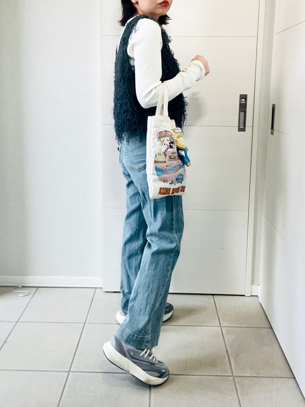 グレー系のベスト、グレー系のスニーカー、ブルー系のデニムパンツを着用したレディースの春コーディネートの5枚目の写真