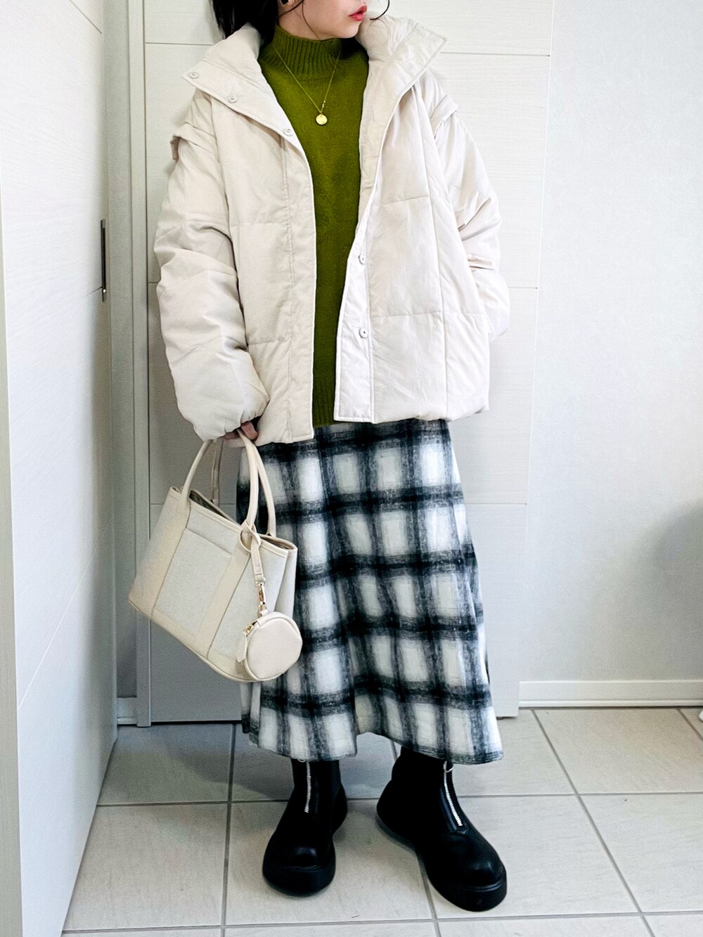 ホワイト系のダウンジャケット/コート、グリーン系のニット/セーター、ホワイト系のスカートを着用したレディースの冬コーディネートの2枚目の写真