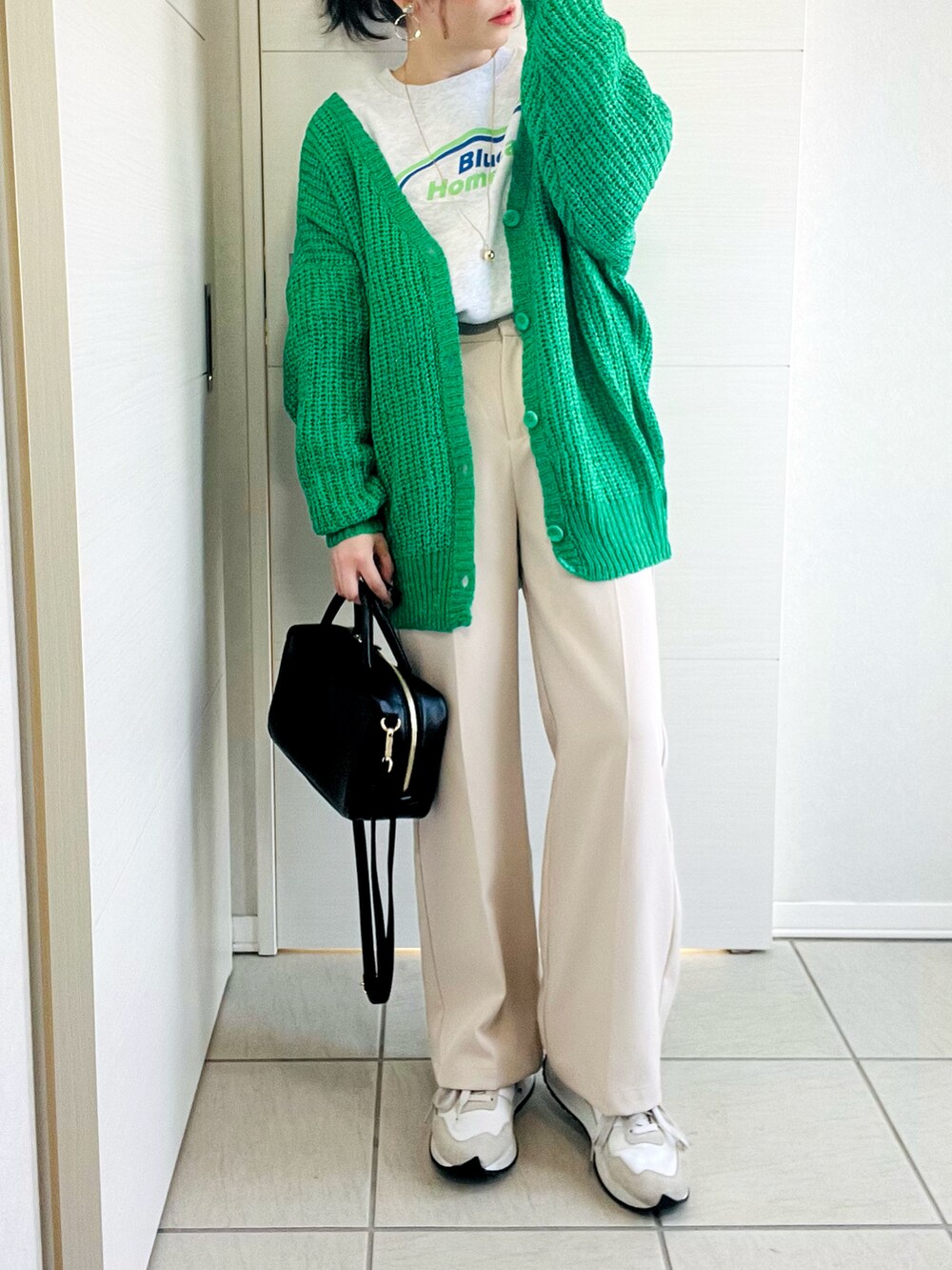 グレー系のスウェット、グリーン系のカーディガン/ボレロ、ホワイト系のスラックスを着用したレディースの春コーディネートの3枚目の写真