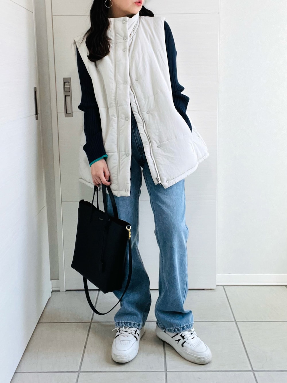 ホワイト系のベスト、ブルー系のデニムパンツ、ブルー系のニット/セーターを着用したレディースの秋コーディネートの4枚目の写真