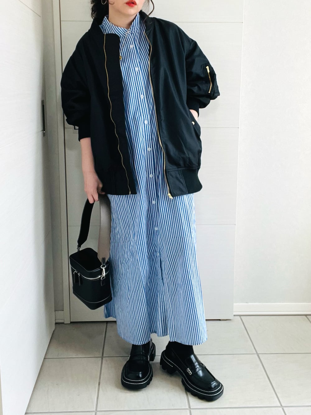 ブルー系のシャツワンピース、ブラック系のブルゾン、ブラック系のローファーを着用したレディースの春コーディネートの3枚目の写真