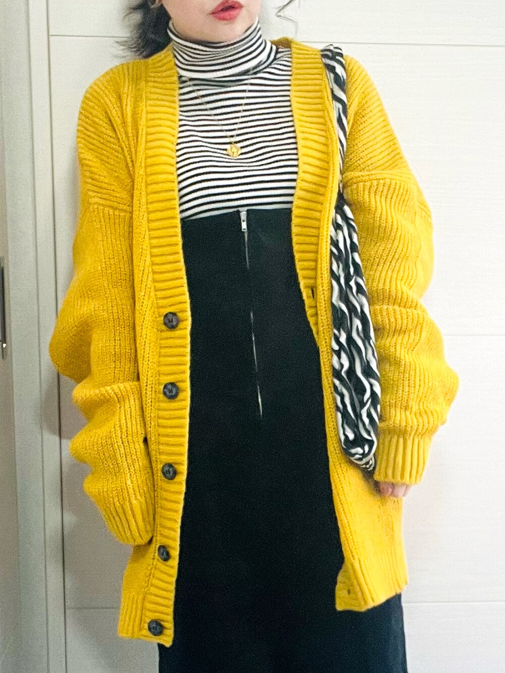 イエロー系のカーディガン/ボレロ、その他のニット/セーター、ブラック系のジャンパースカートを着用したレディースの冬コーディネートの2枚目の写真