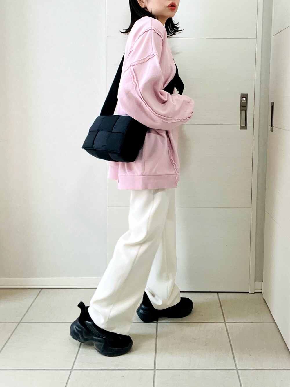 ピンク系のスウェット、ホワイト系のスラックス、ブラック系のスニーカーを着用したレディースの冬コーディネートの5枚目の写真