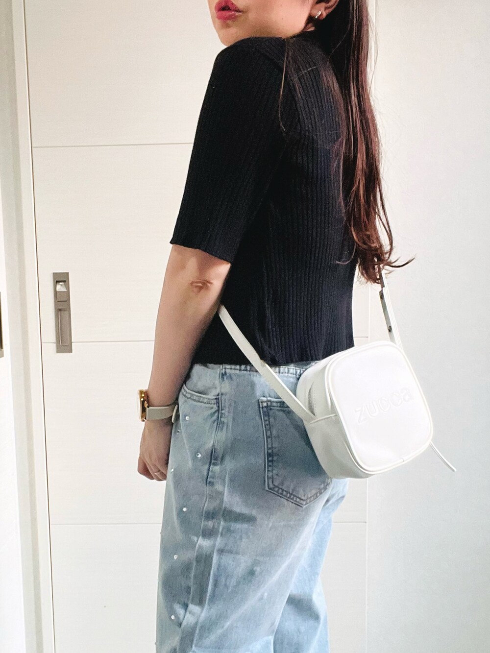 ブラック系のニット/セーター、ホワイト系のキャミソール、ブルー系のデニムパンツを着用したレディースの夏コーディネートの3枚目の写真