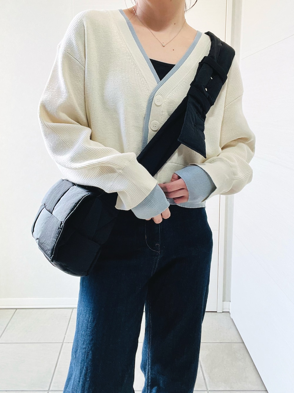 ホワイト系のカーディガン/ボレロ、グレー系のスニーカー、ブルー系のデニムパンツを着用したレディースの春コーディネートの2枚目の写真