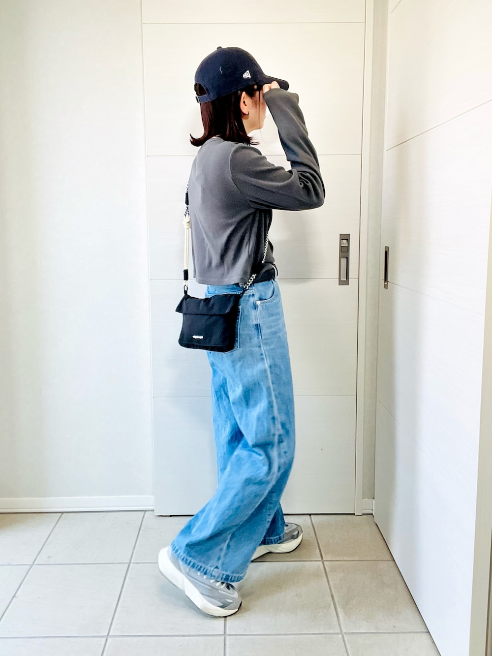 グレー系のスニーカー、グレー系のTシャツ/カットソー、ブラック系のショルダーバッグを着用したレディースの夏コーディネートの4枚目の写真
