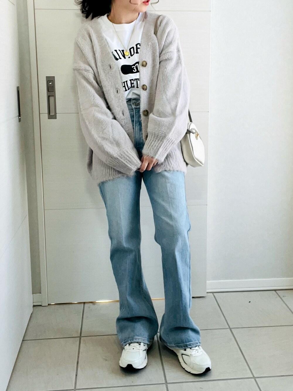 ホワイト系のTシャツ/カットソー、グレー系のカーディガン/ボレロ、ブルー系のデニムパンツを着用したレディースの冬コーディネートの3枚目の写真