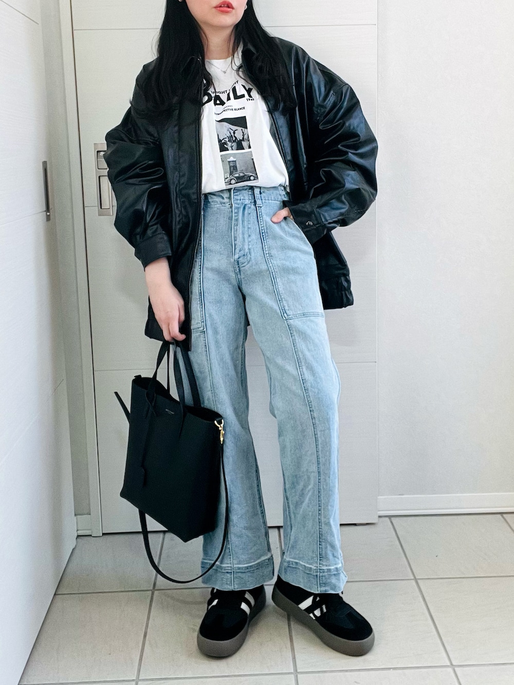 ブラック系のブルゾン、ホワイト系のTシャツ/カットソー、ブルー系のデニムパンツを着用したレディースの冬コーディネートの4枚目の写真