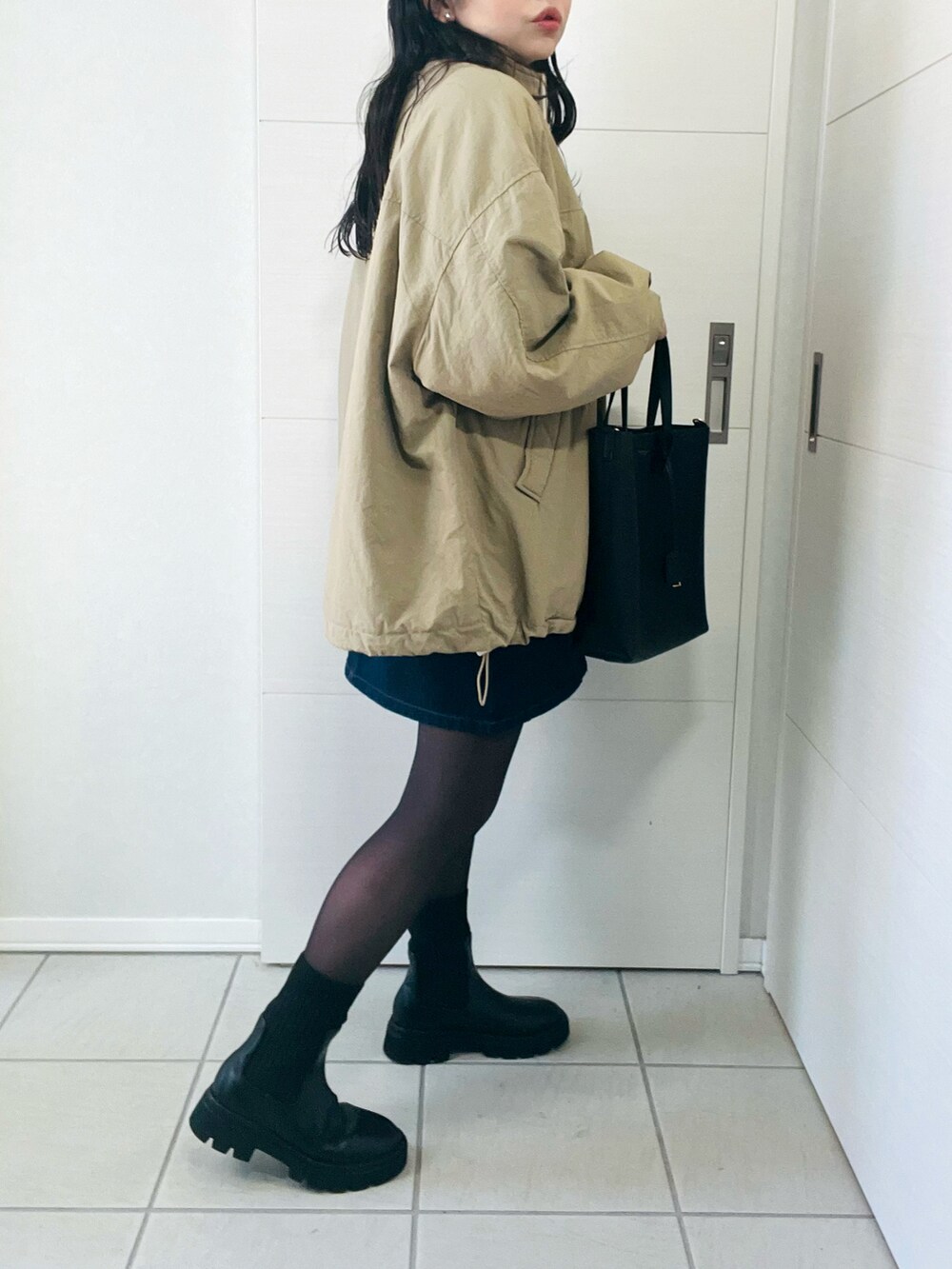 ベージュ系のブルゾン、ホワイト系のニット/セーター、ブルー系のデニムスカートを着用したレディースの秋コーディネートの5枚目の写真