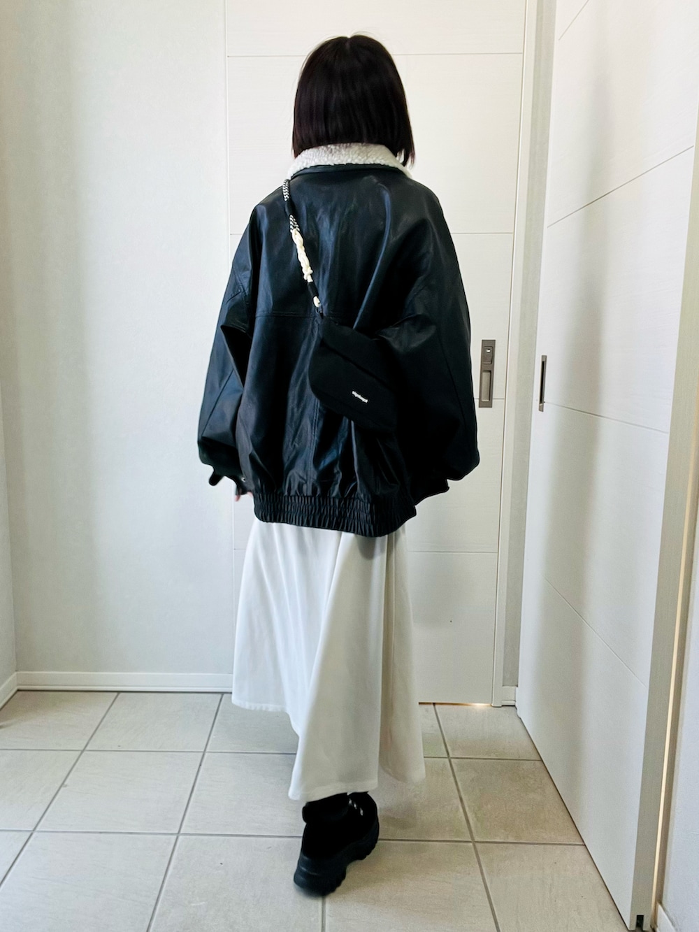 ブラック系のブルゾン、ホワイト系のワンピース、ブラック系のブーツを着用したレディースの冬コーディネートの3枚目の写真