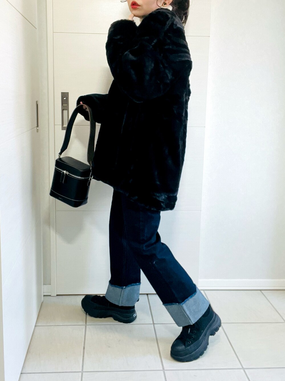 ブラック系のノーカラーコート、ベージュ系のニット/セーター、ブルー系のデニムパンツを着用したレディースの冬コーディネートの5枚目の写真