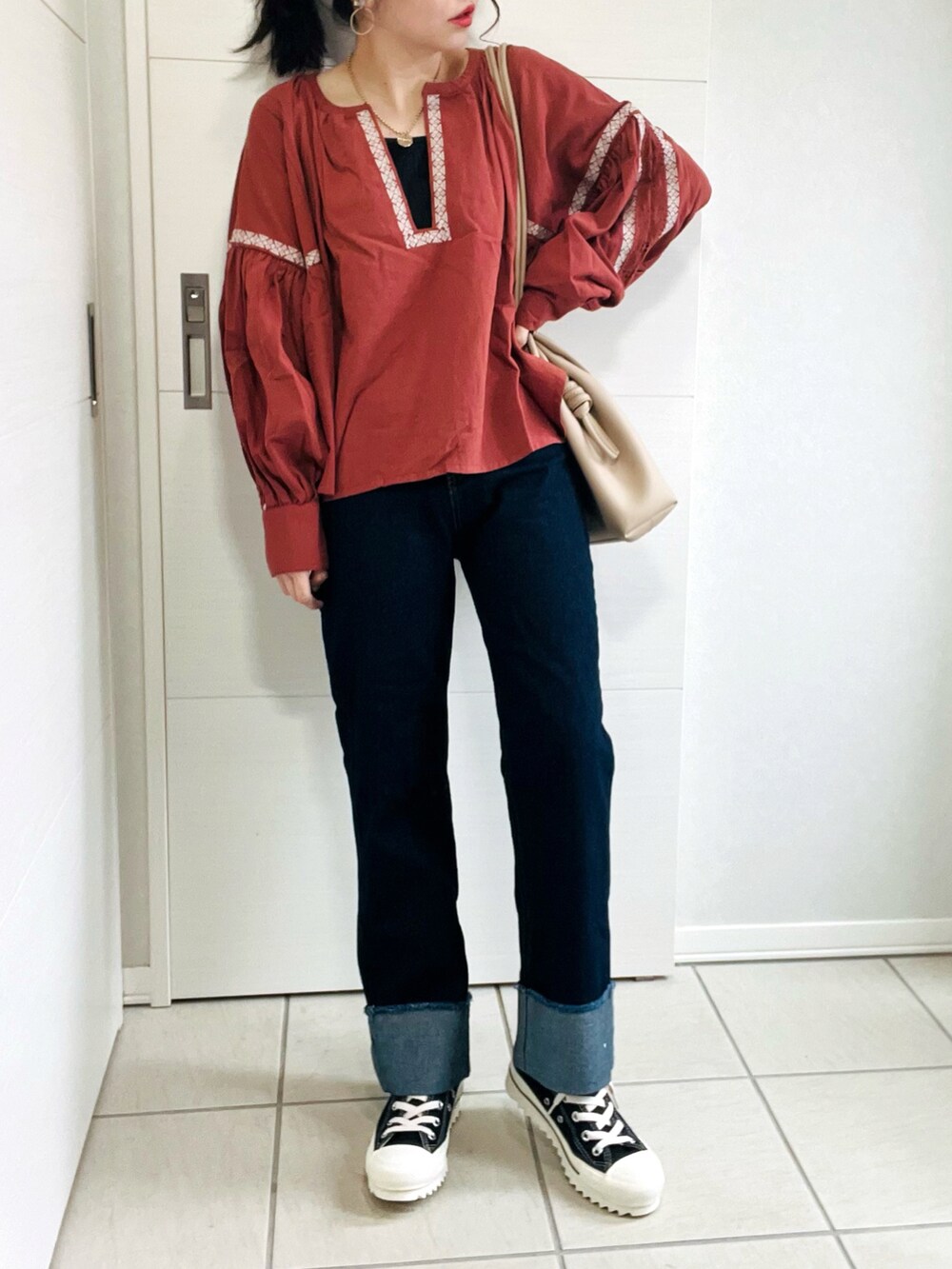 ブラウン系のシャツ/ブラウス、ブルー系のデニムパンツ、ブラック系のスニーカーを着用したレディースの秋コーディネートの2枚目の写真