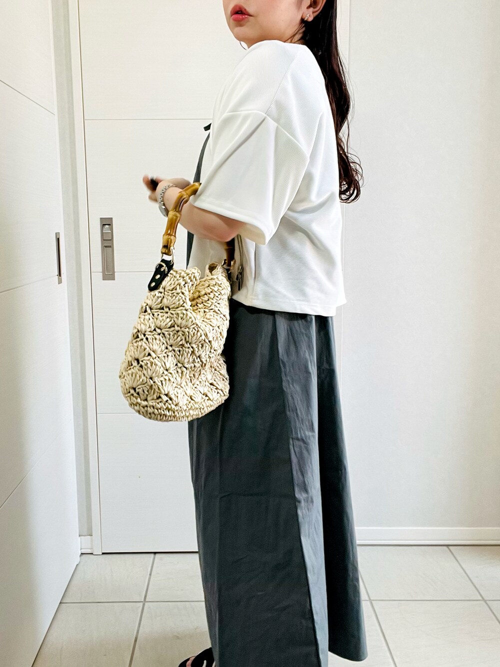 グレー系のワンピース、ブラック系のサンダル、ベージュ系のショルダーバッグを着用したレディースの夏コーディネートの3枚目の写真