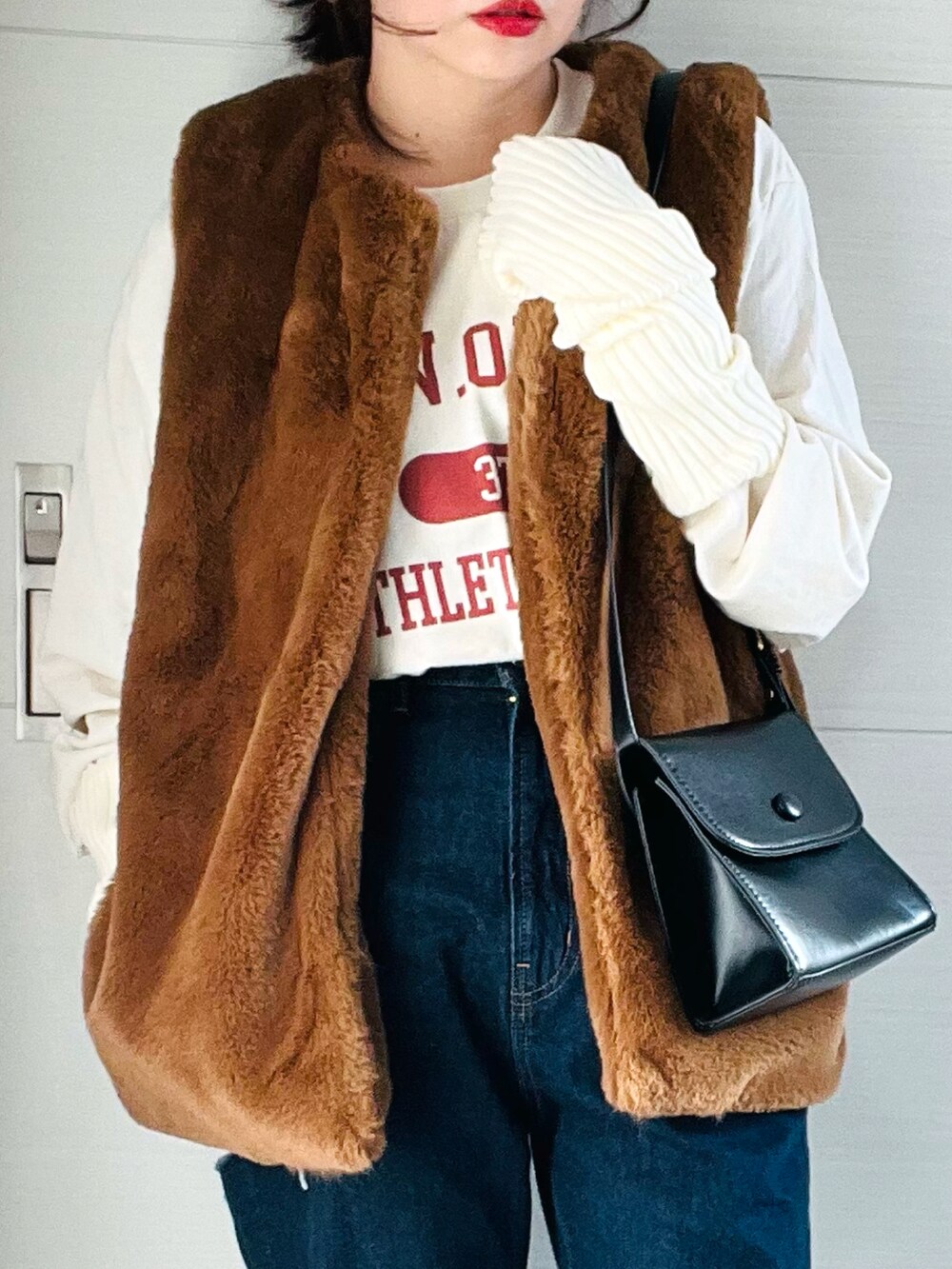 ベージュ系のTシャツ/カットソー、ブラウン系のベスト、ブルー系のデニムパンツを着用したレディースの秋コーディネートの5枚目の写真