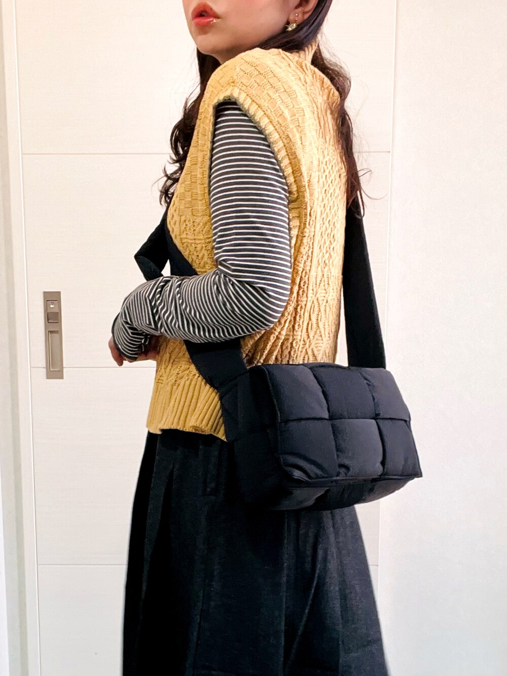 イエロー系のベスト、グレー系のTシャツ/カットソー、ブラック系のスカートを着用したレディースの秋コーディネートの2枚目の写真