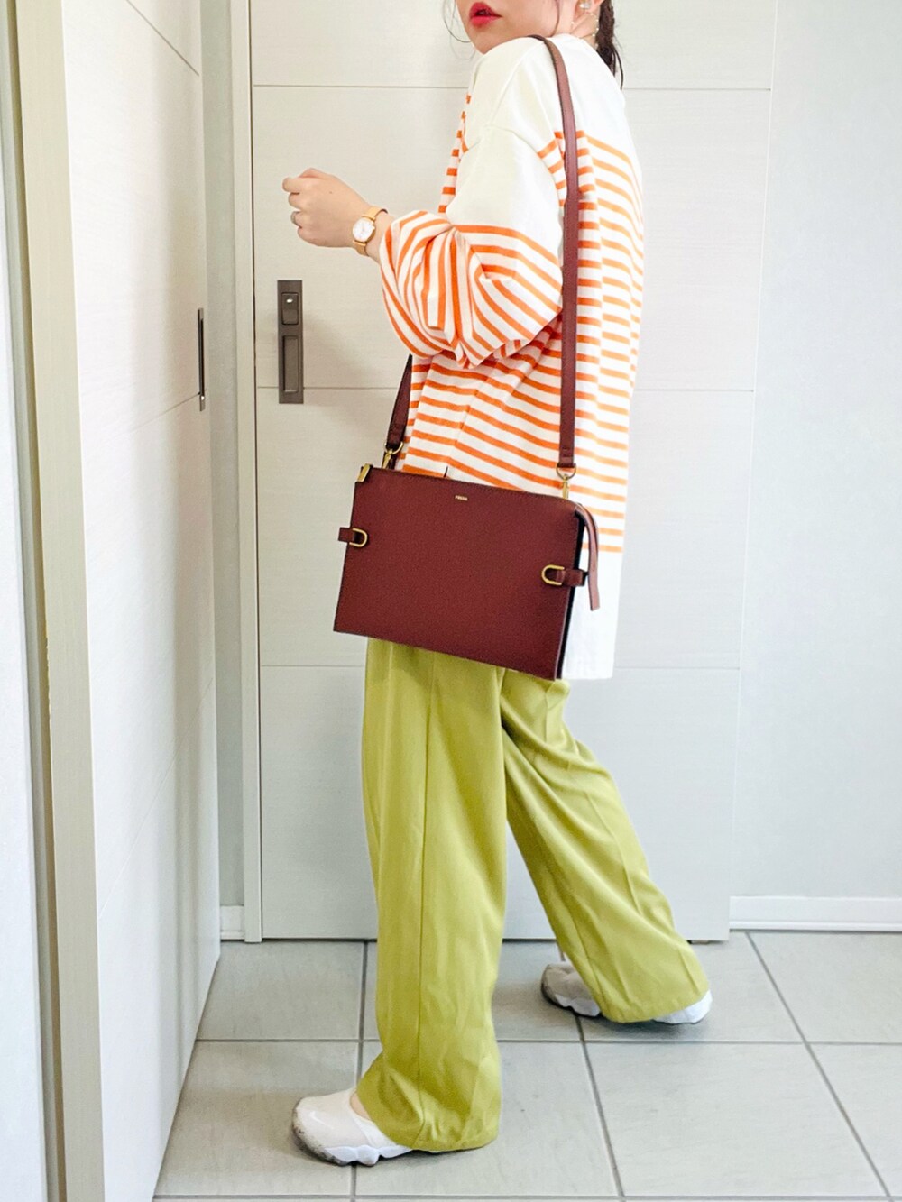 オレンジ系のTシャツ/カットソー、グリーン系のスラックス、ホワイト系のスニーカーを着用したレディースの春コーディネートの5枚目の写真