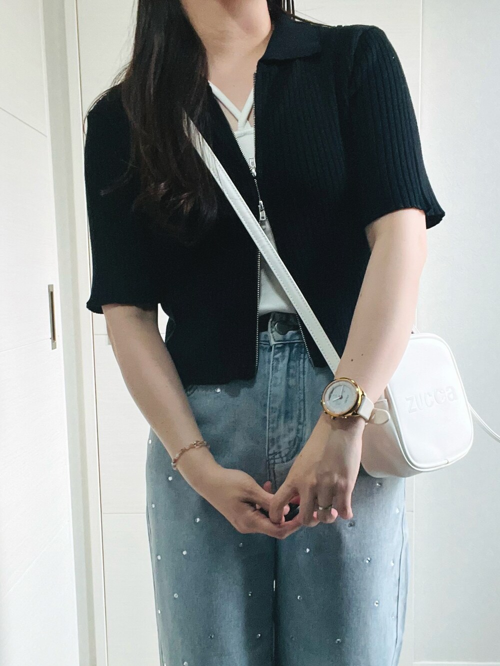 ブラック系のニット/セーター、ホワイト系のキャミソール、ブルー系のデニムパンツを着用したレディースの夏コーディネートの2枚目の写真