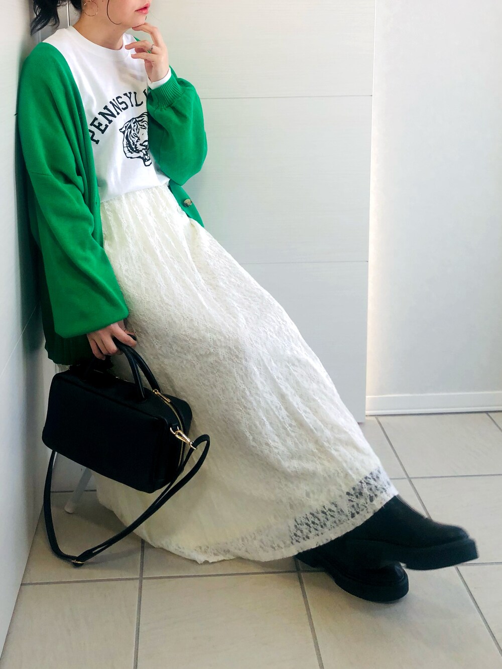 グリーン系のカーディガン/ボレロ、ホワイト系のTシャツ/カットソー、ホワイト系のスカートを着用したレディースの冬コーディネートの2枚目の写真