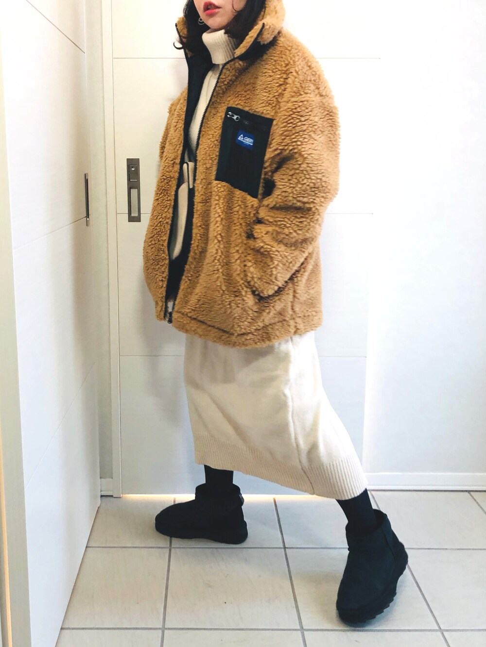 ベージュ系のブルゾン、ホワイト系のワンピース、ブラック系のブーツを着用したレディースの冬コーディネートの3枚目の写真