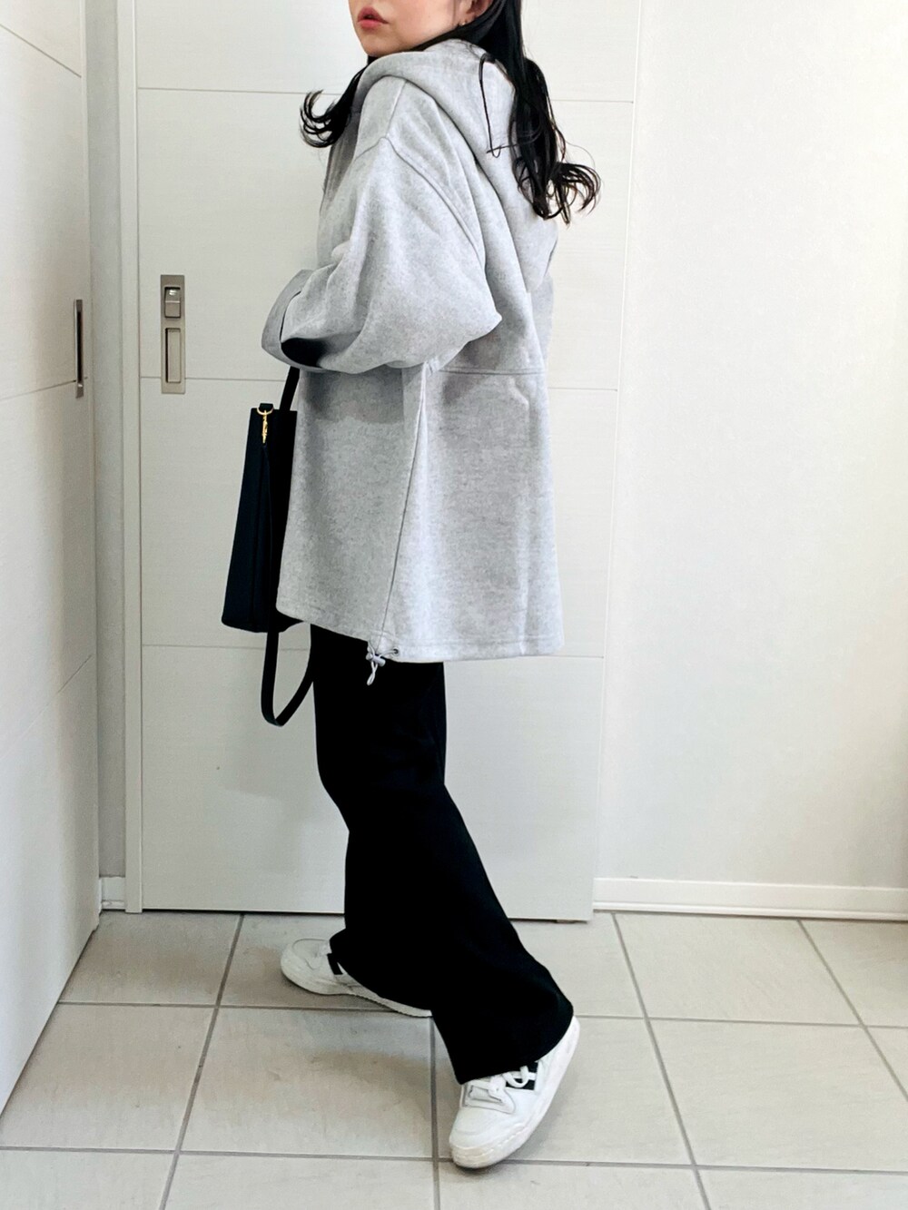 グレー系のパーカー、グレー系のTシャツ/カットソー、ブラック系のスラックスを着用したレディースの冬コーディネートの5枚目の写真