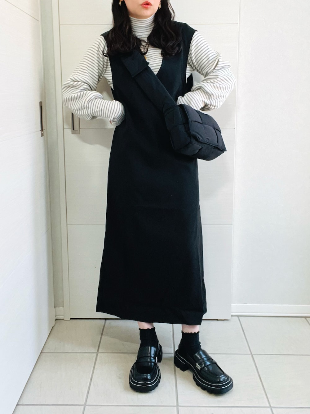 ブラック系のジャンパースカート、グレー系のニット/セーター、ブラック系のローファーを着用したレディースの秋コーディネートの2枚目の写真