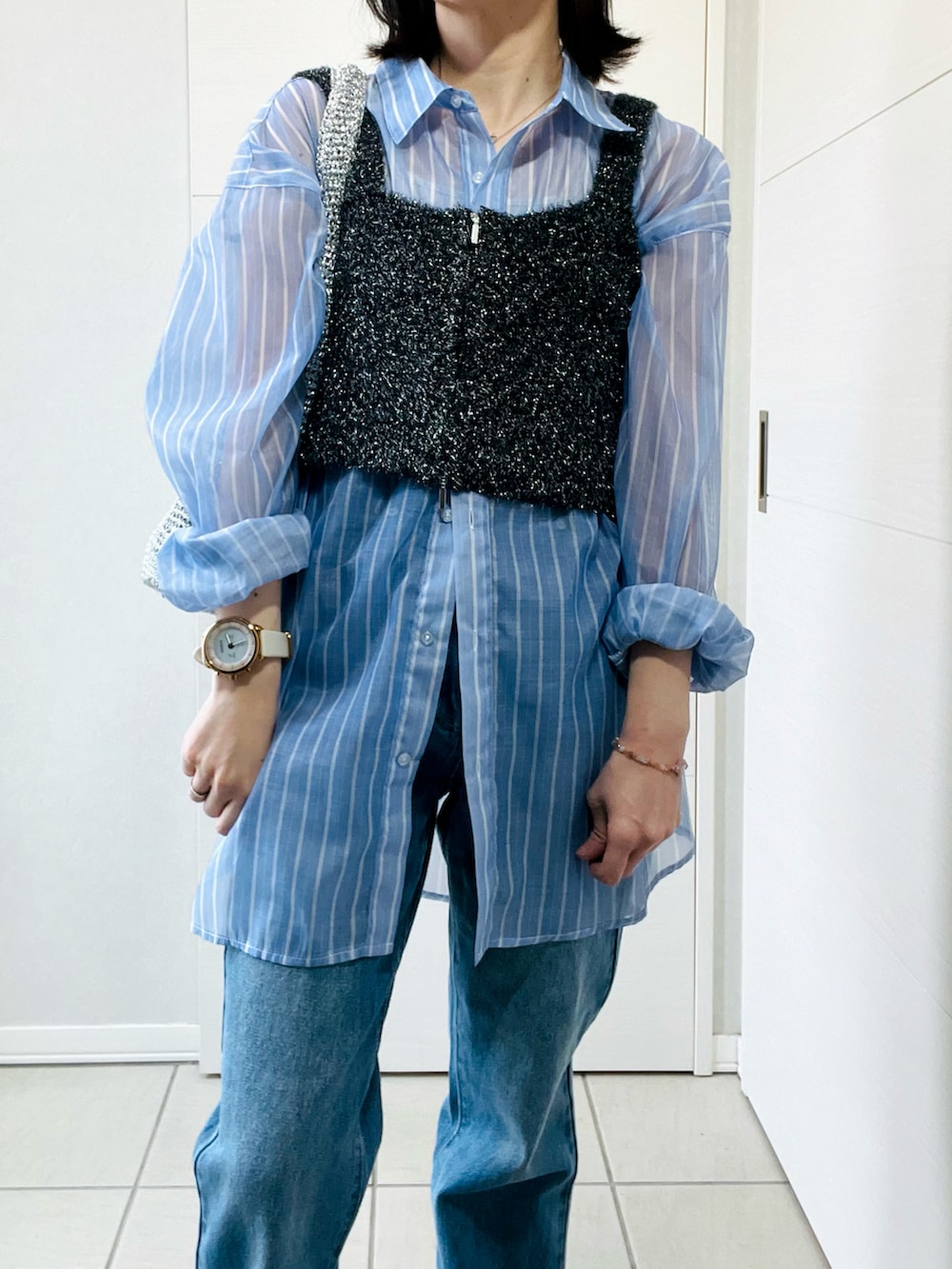 ブルー系のシャツ/ブラウス、ブラック系のベスト、ブルー系のデニムパンツを着用したレディースの春コーディネートの3枚目の写真