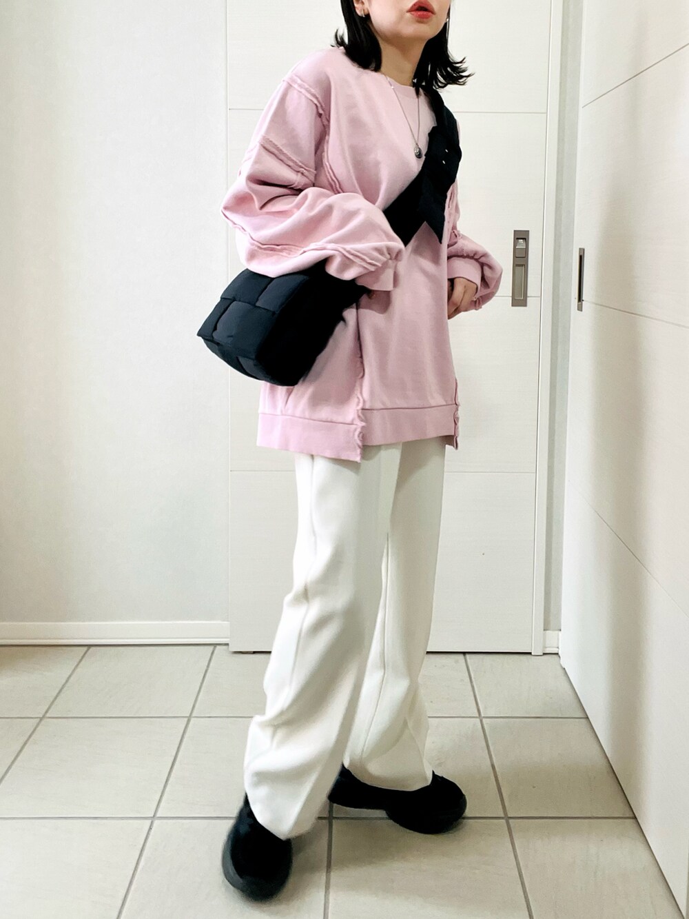ピンク系のスウェット、ホワイト系のスラックス、ブラック系のスニーカーを着用したレディースの冬コーディネートの4枚目の写真
