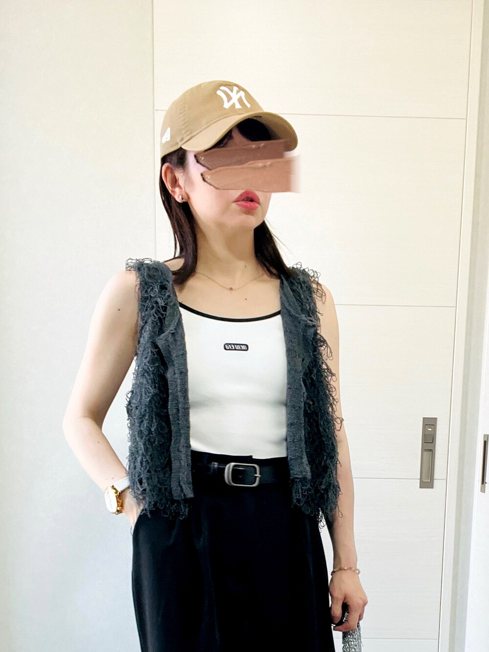 ホワイト系のキャミソール、グレー系のベスト、ブラック系のスラックスを着用したレディースの夏コーディネートの3枚目の写真