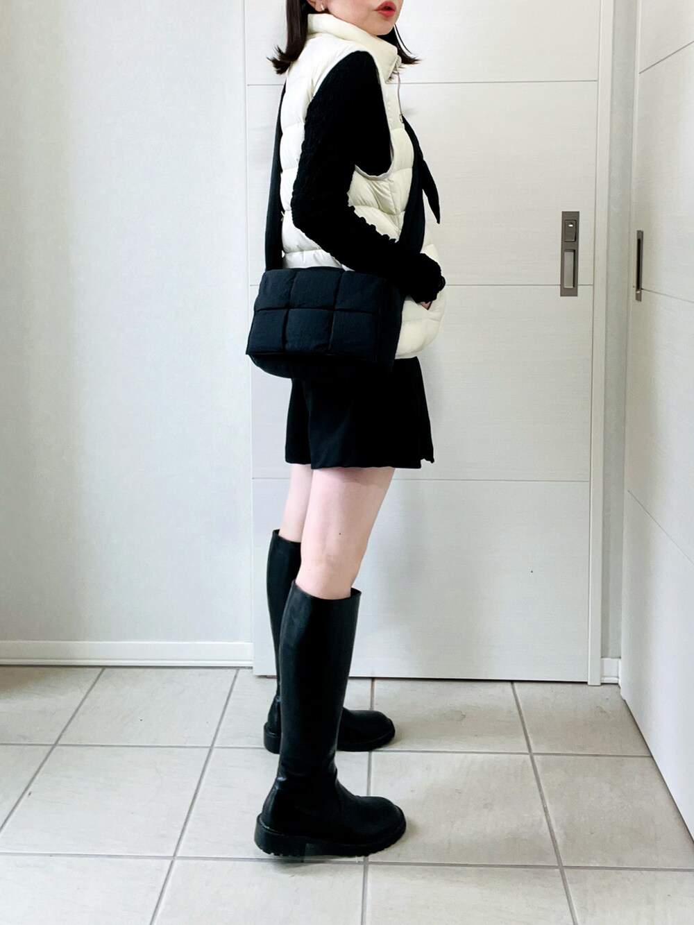 ホワイト系のダウンベスト、ブラック系のその他パンツ、ブラック系のブーツを着用したレディースの秋コーディネートの5枚目の写真