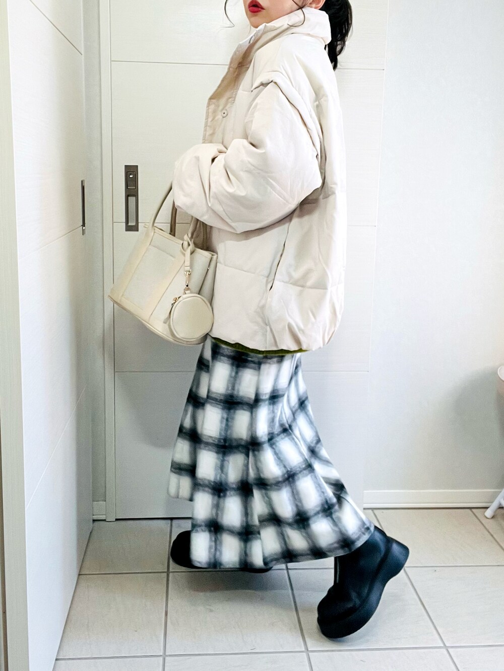 ホワイト系のダウンジャケット/コート、グリーン系のニット/セーター、ホワイト系のスカートを着用したレディースの冬コーディネートの4枚目の写真