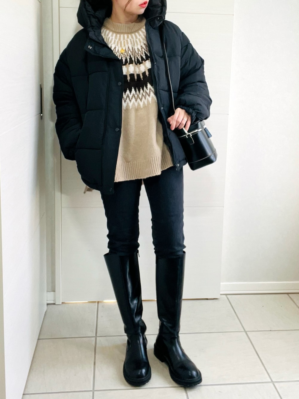 ブラック系のダウンジャケット/コート、ベージュ系のニット/セーター、ブラック系のデニムパンツを着用したレディースの冬コーディネートの3枚目の写真