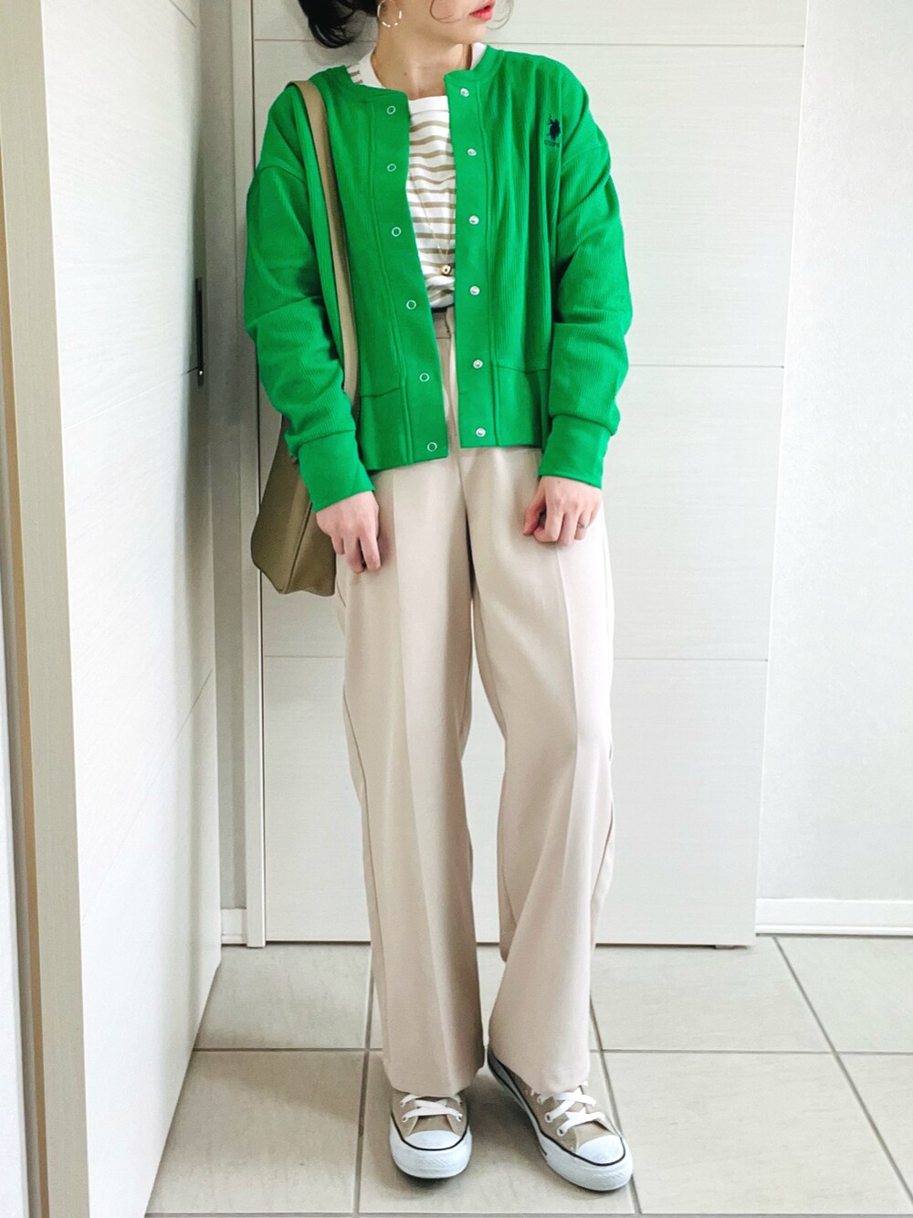 グリーン系のカーディガン/ボレロ、ベージュ系のTシャツ/カットソー、ホワイト系のスラックスを着用したレディースの春コーディネートの3枚目の写真