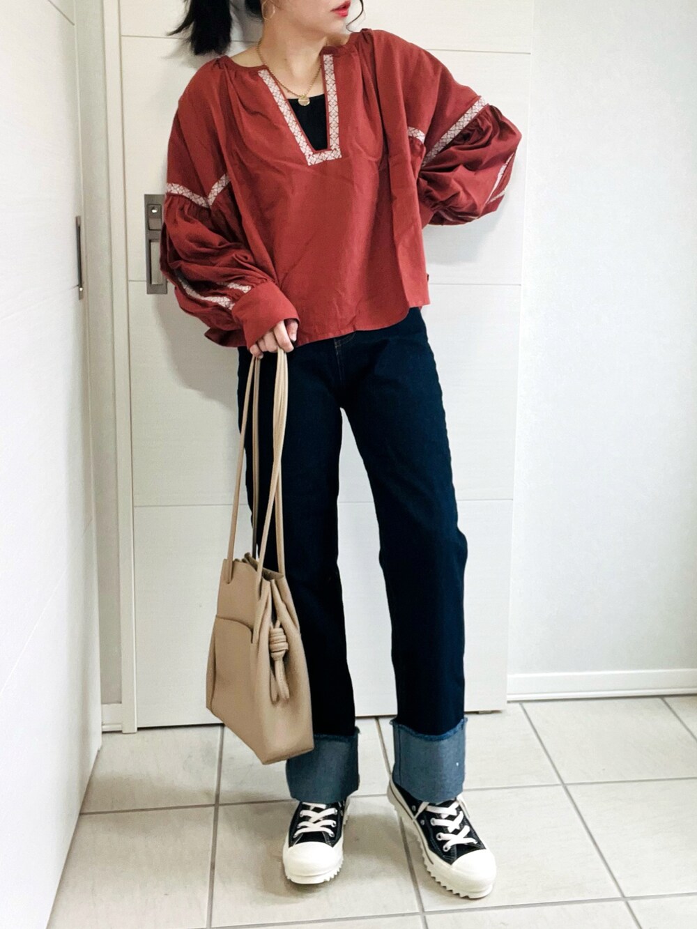 ブラウン系のシャツ/ブラウス、ブルー系のデニムパンツ、ブラック系のスニーカーを着用したレディースの秋コーディネートの3枚目の写真