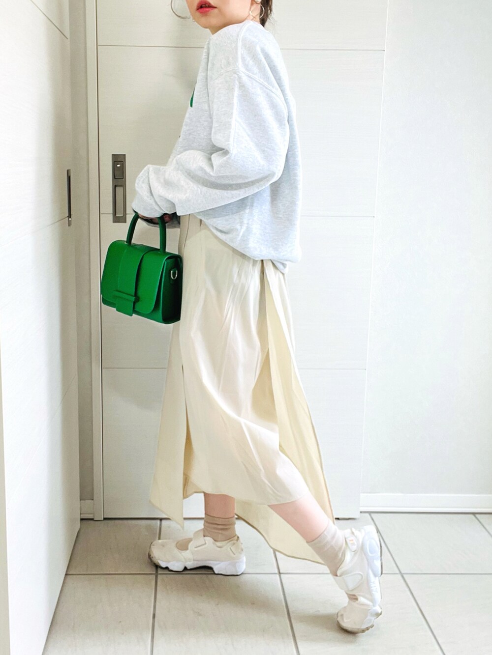 グレー系のスウェット、ベージュ系のスカート、ホワイト系のスニーカーを着用したレディースの春コーディネートの3枚目の写真