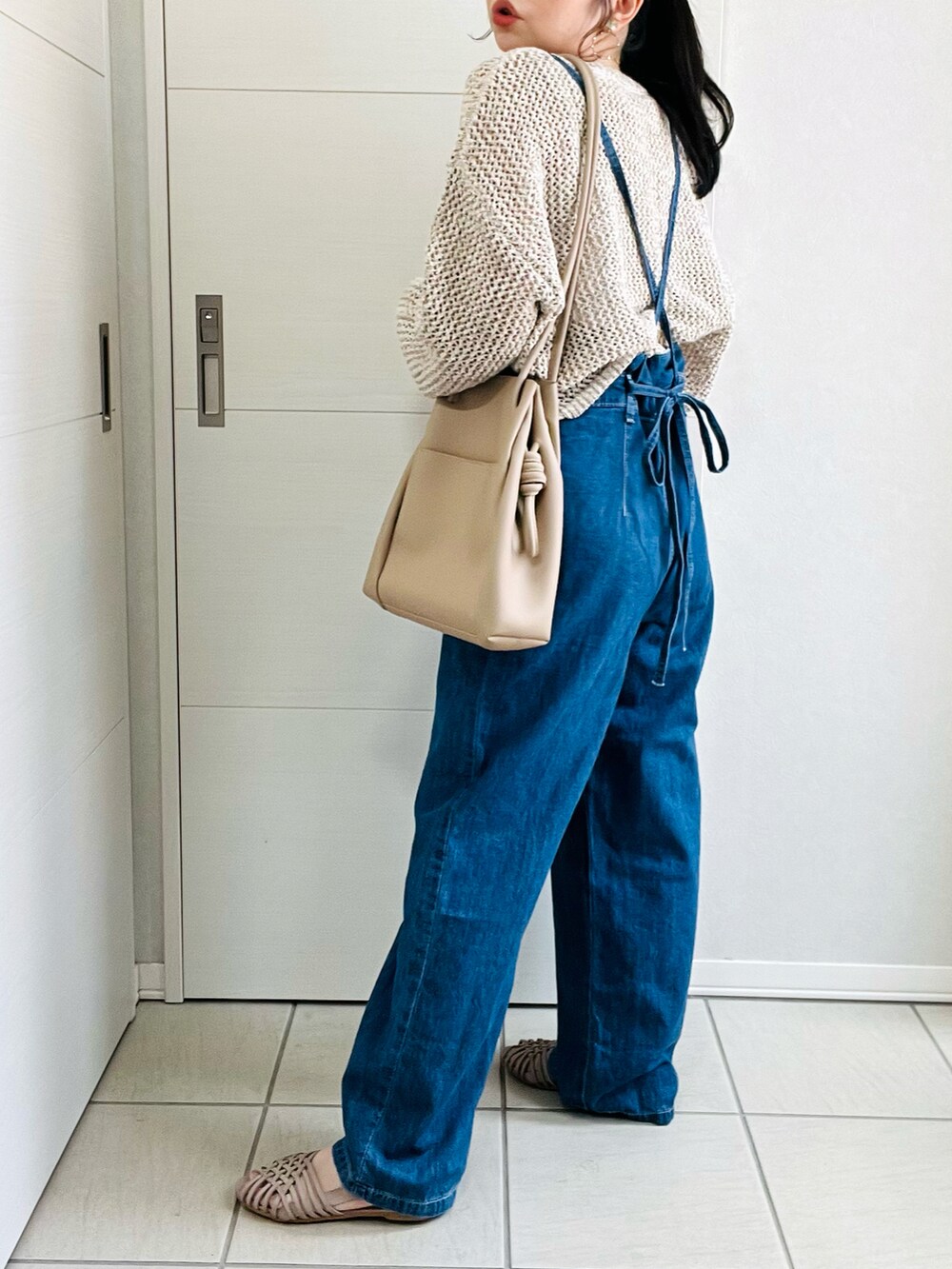 ブルー系のサロペット/オーバーオール、ベージュ系のニット/セーター、グレー系のサンダルを着用したレディースの春コーディネートの3枚目の写真