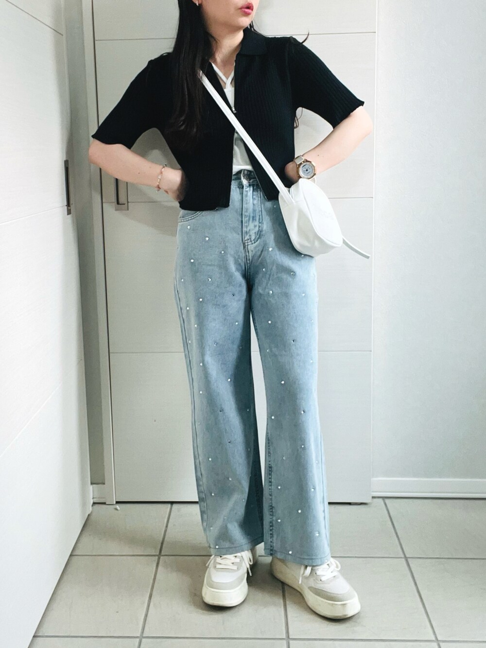 ブラック系のニット/セーター、ホワイト系のキャミソール、ブルー系のデニムパンツを着用したレディースの夏コーディネートの4枚目の写真