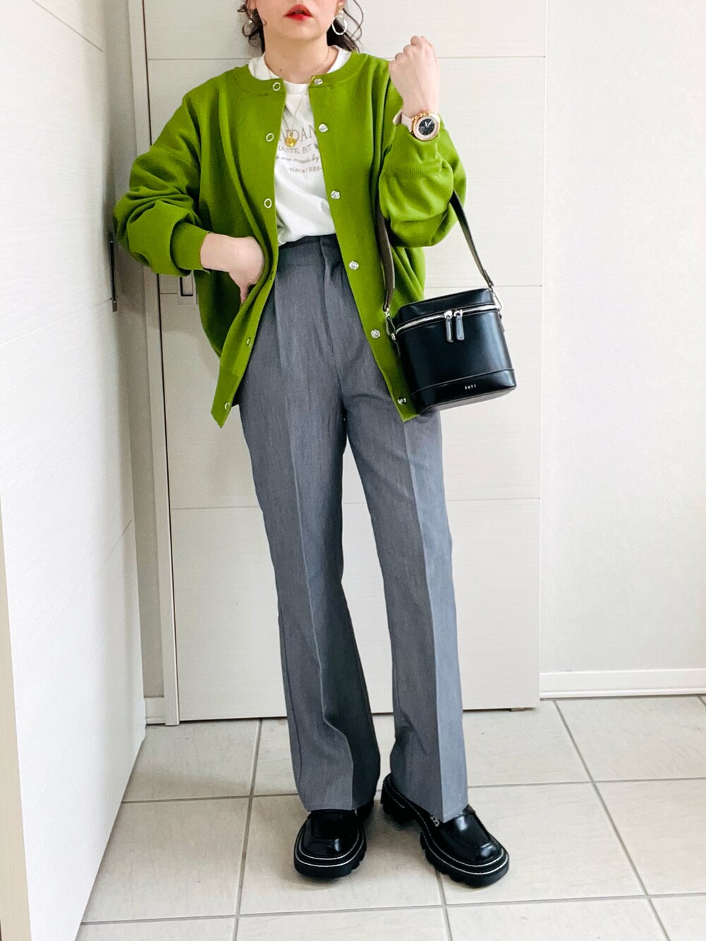 グリーン系のカーディガン/ボレロ、ホワイト系のTシャツ/カットソー、グレー系のスラックスを着用したレディースの春コーディネートの3枚目の写真