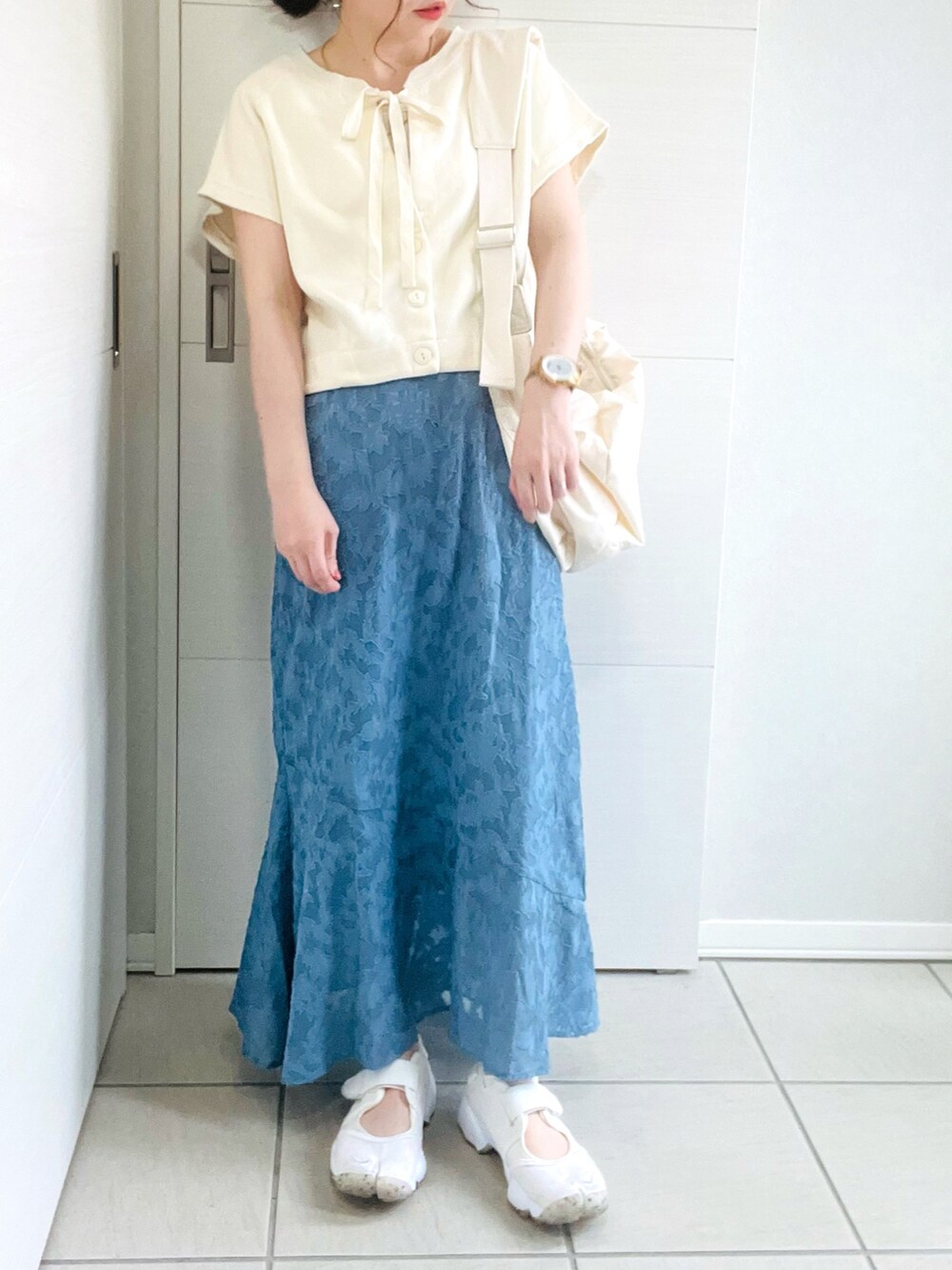 ホワイト系のカーディガン/ボレロ、ブルー系のスカート、ホワイト系のサンダルを着用したレディースの夏コーディネートの2枚目の写真
