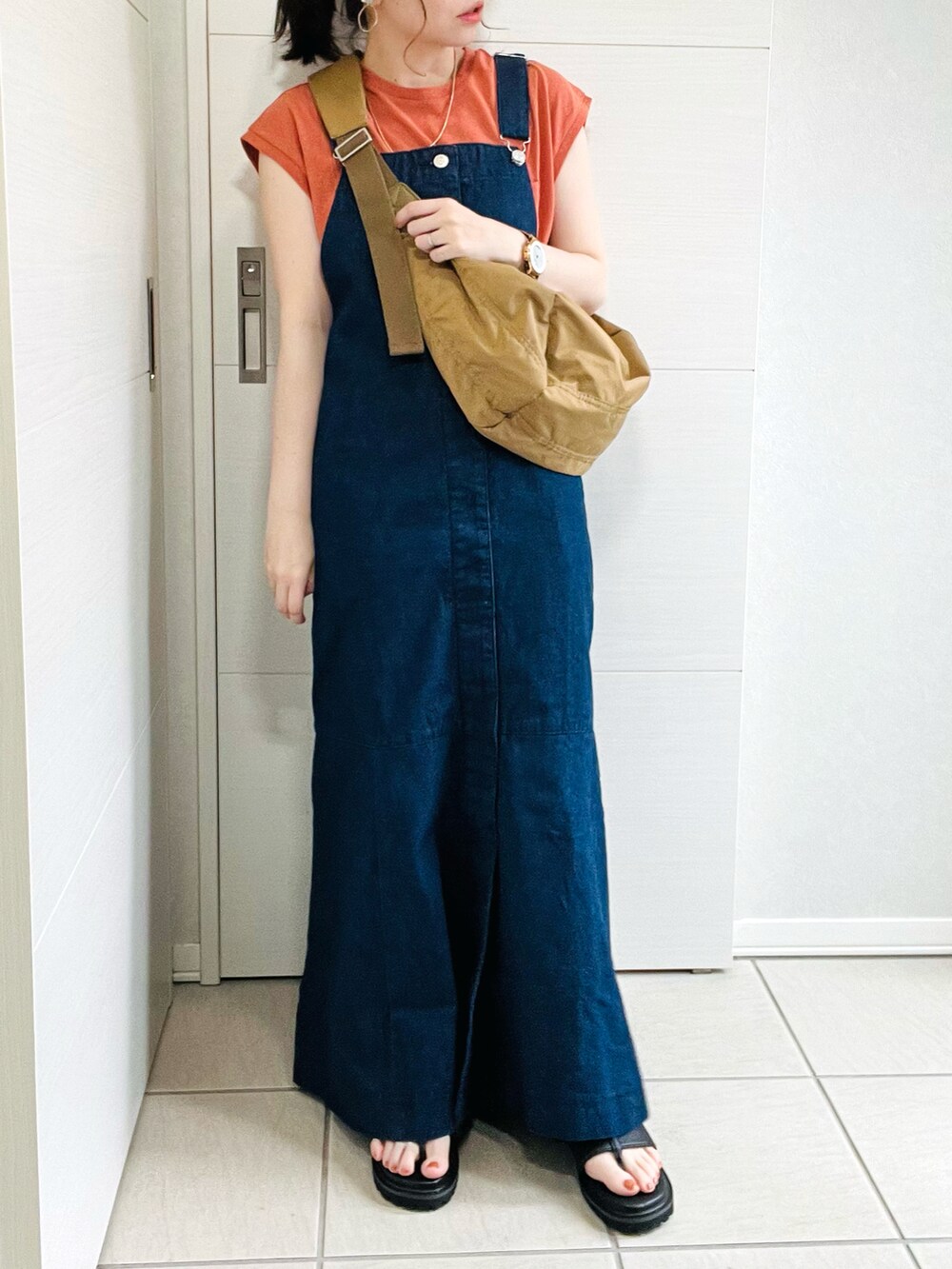 グリーン系のショルダーバッグ、オレンジ系のTシャツ/カットソー、ブルー系のジャンパースカートを着用したレディースの夏コーディネートの4枚目の写真