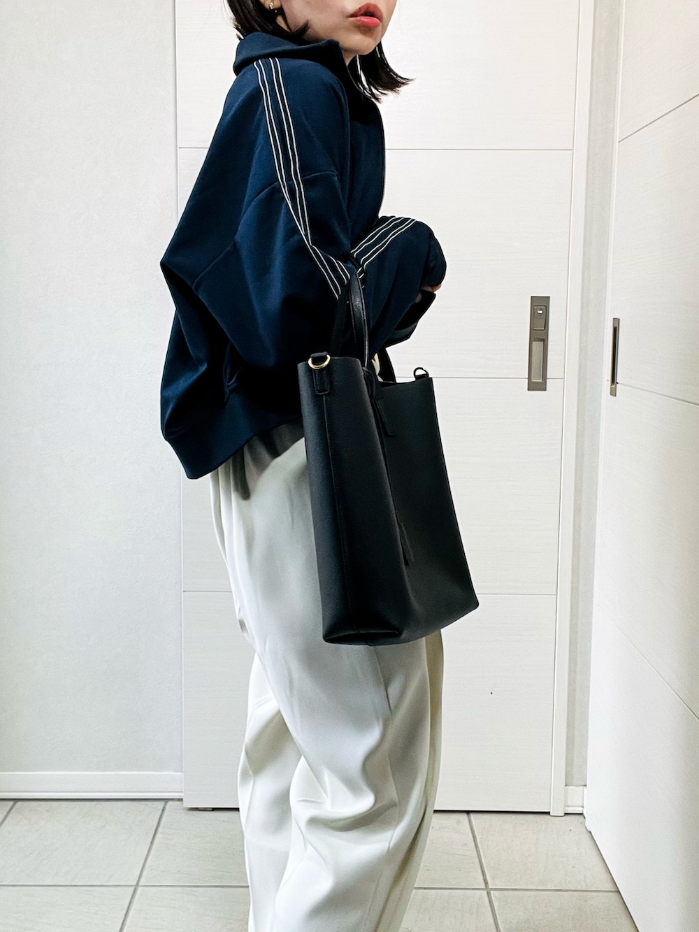 ブルー系のブルゾン、ホワイト系のスラックス、ブラック系のスニーカーを着用したレディースの秋コーディネートの3枚目の写真