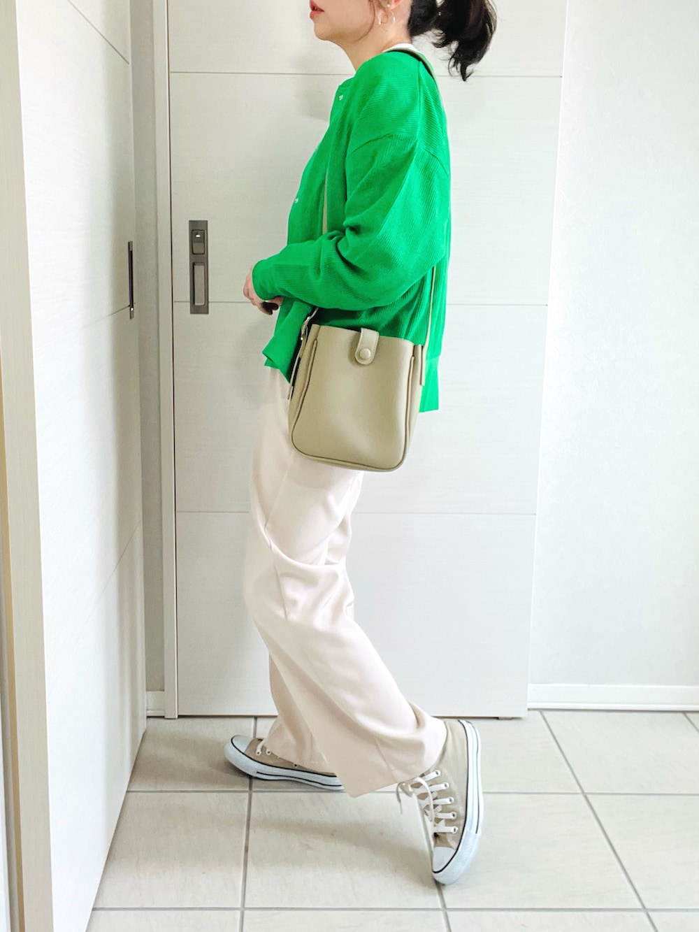 グリーン系のカーディガン/ボレロ、ベージュ系のTシャツ/カットソー、ホワイト系のスラックスを着用したレディースの春コーディネートの4枚目の写真