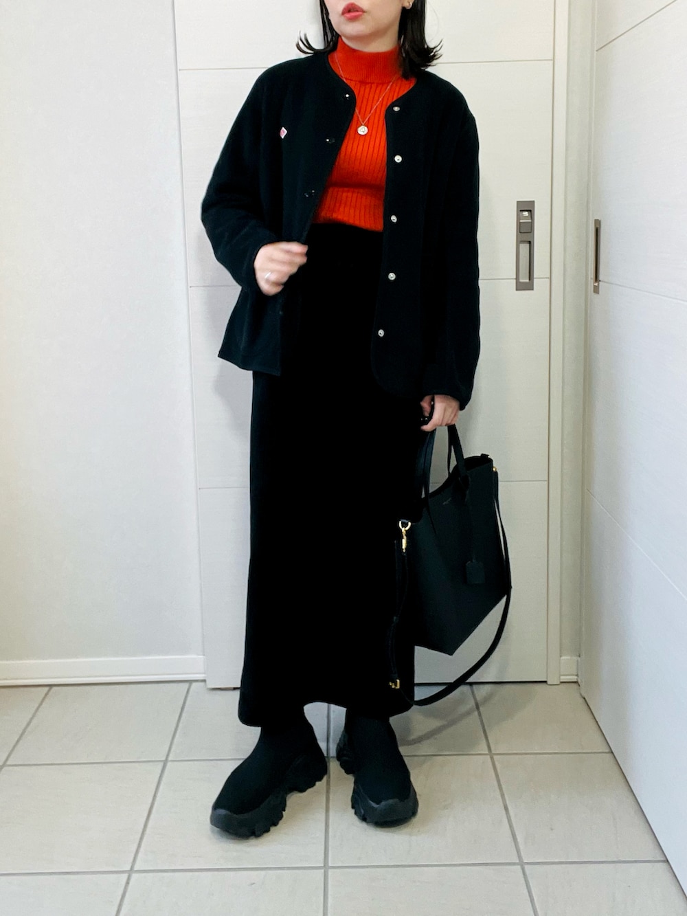 ブラック系のノーカラージャケット、ブラック系のスカート、ブラック系のブーツを着用したレディースの冬コーディネートの3枚目の写真