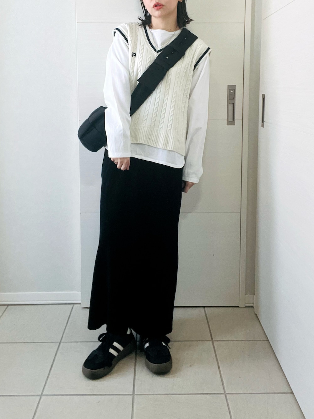 ホワイト系のTシャツ/カットソー、ホワイト系のベスト、ブラック系のスカートを着用したレディースの冬コーディネートの3枚目の写真