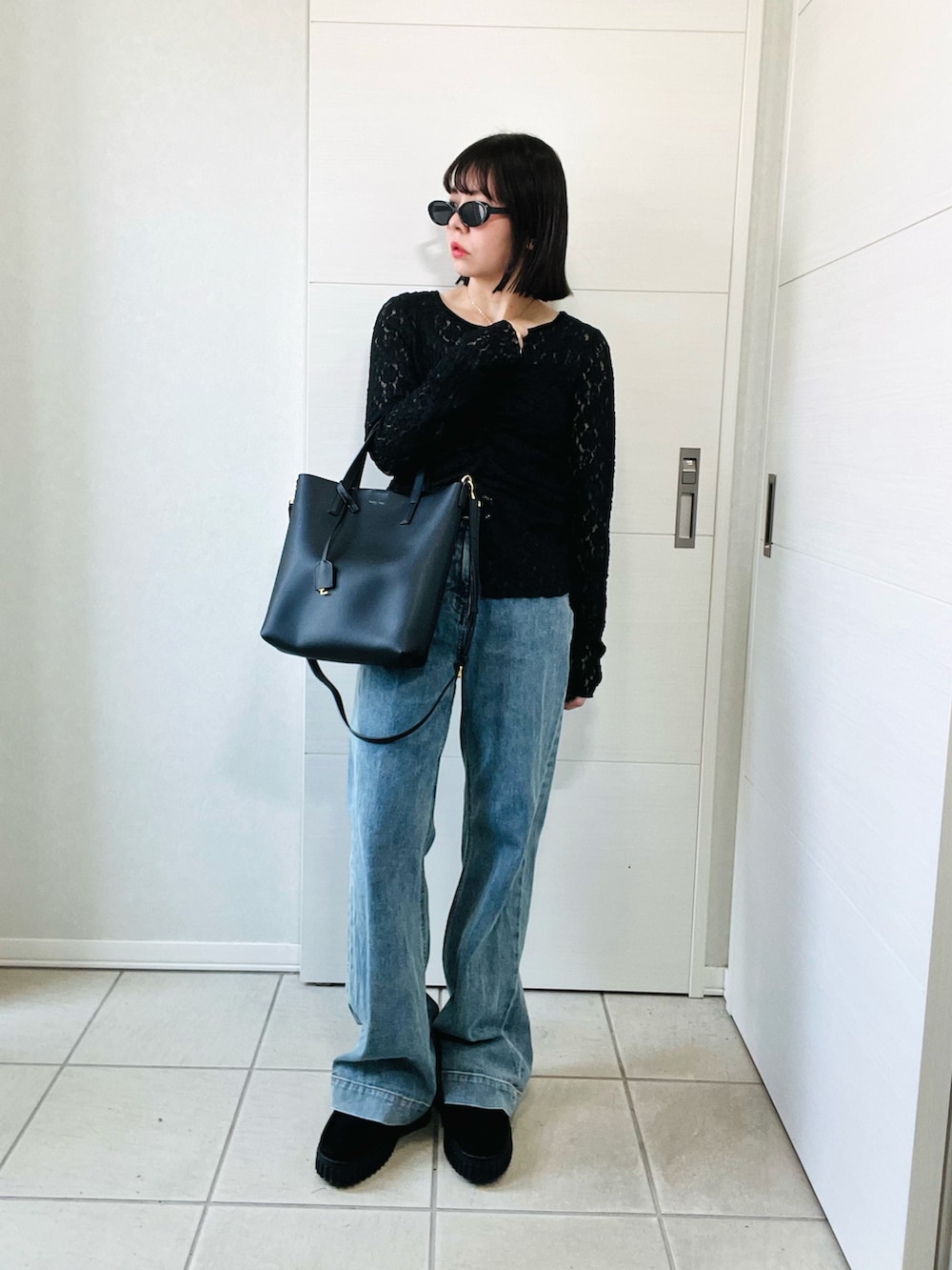 ブラック系のシャツ/ブラウス、ブラック系のブーツ、ブルー系のデニムパンツを着用したレディースの秋コーディネートの5枚目の写真