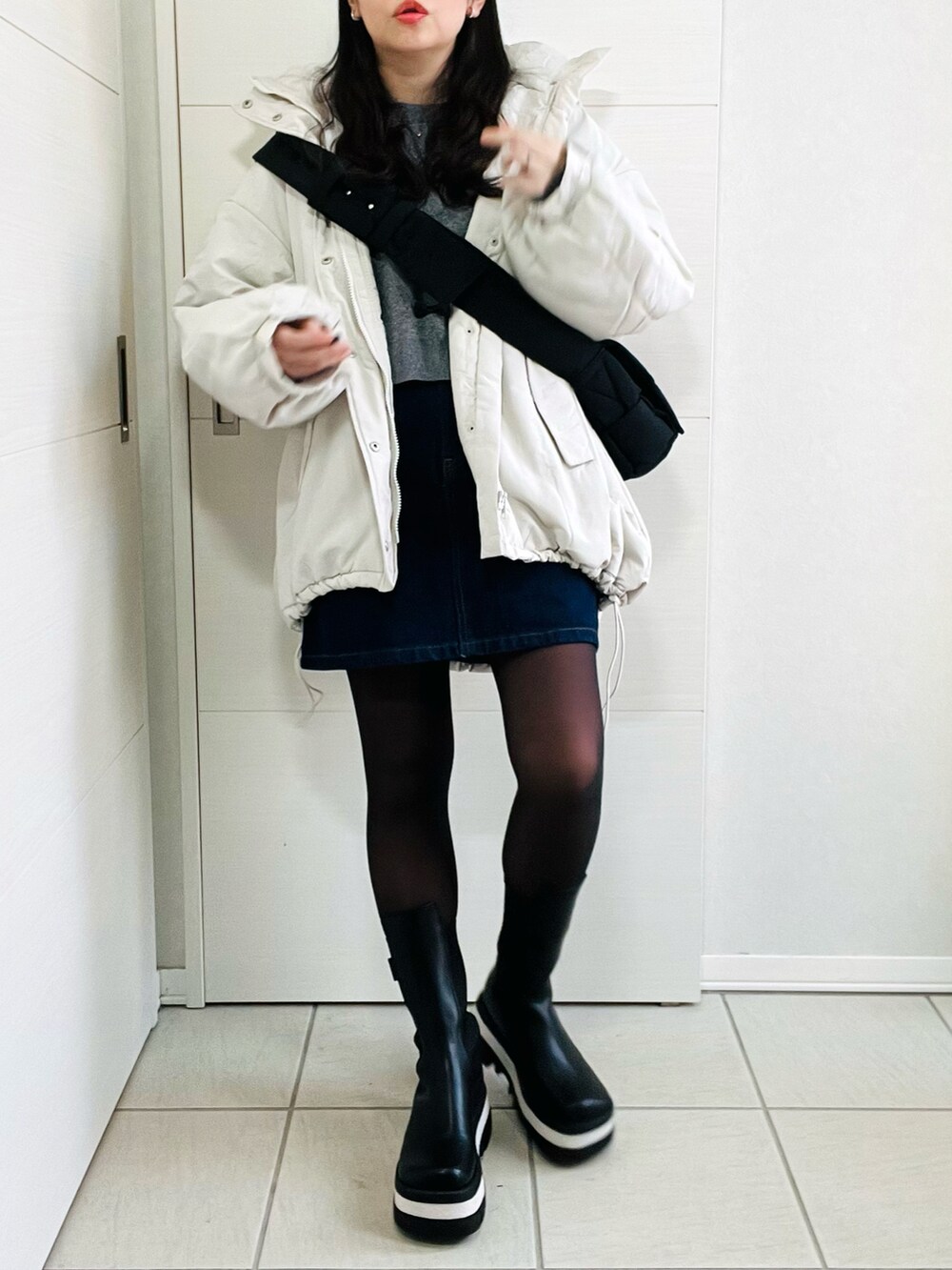 ホワイト系のダウンジャケット/コート、グレー系のニット/セーター、ブルー系のデニムスカートを着用したレディースの冬コーディネートの4枚目の写真