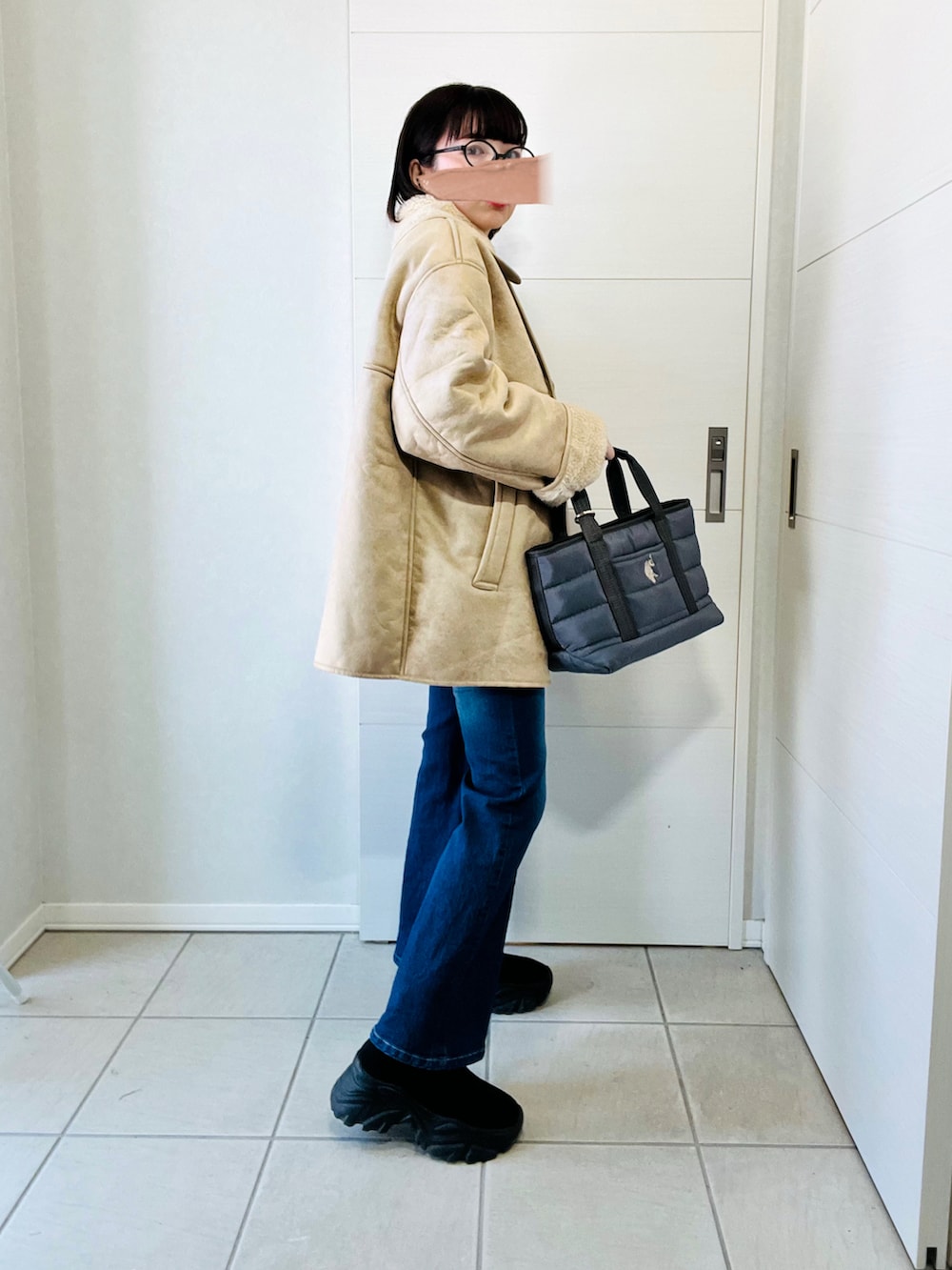 ベージュ系のムートンコート、ブルー系のデニムパンツ、グレー系のトートバッグを着用したレディースの冬コーディネートの5枚目の写真