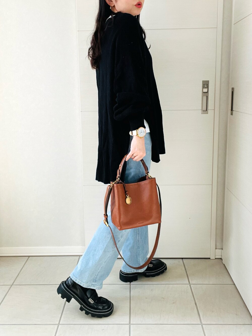 ブラウン系のショルダーバッグ、ホワイト系のTシャツ/カットソー、ブラック系のニット/セーターを着用したレディースの秋コーディネートの5枚目の写真