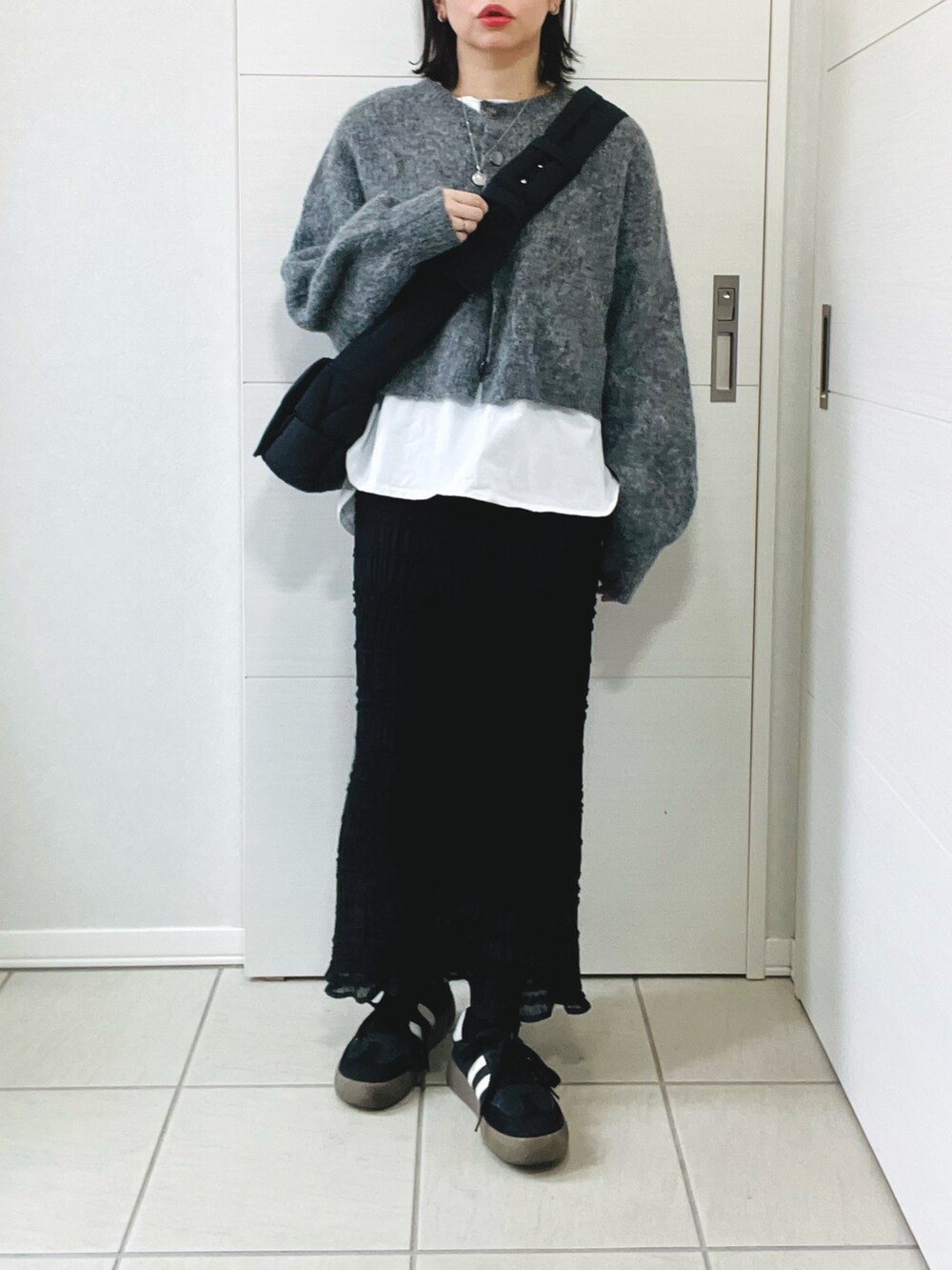 グレー系のカーディガン/ボレロ、ホワイト系のTシャツ/カットソー、ブラック系のスカートを着用したレディースの冬コーディネートの4枚目の写真